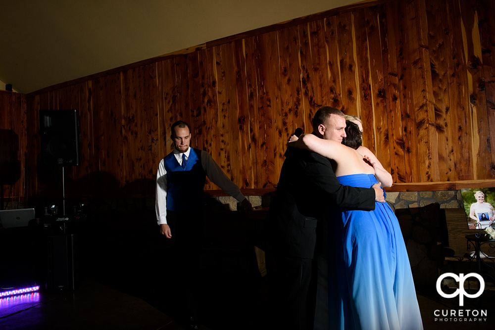 Maid of honor hugging the bride and groom