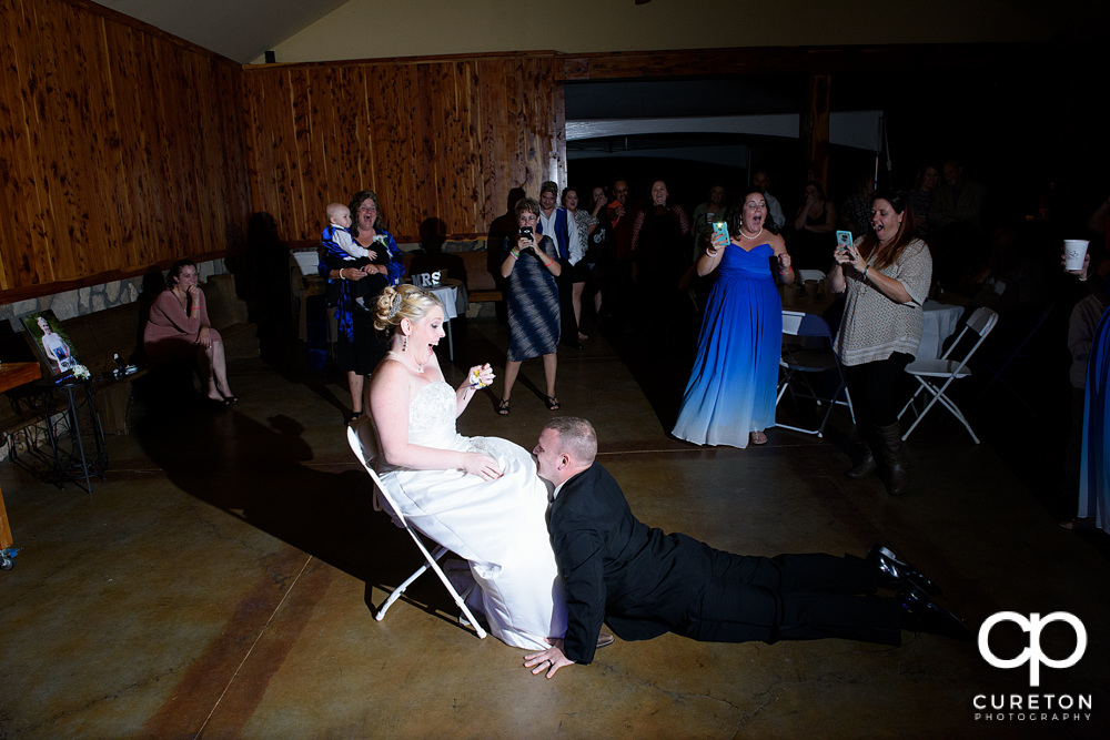 Groom dancing as he takes the garter off.