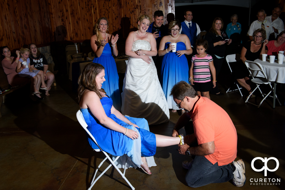 Man who caught the garter putting it back on the woman who caught the bouquet.