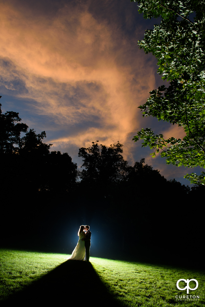 Bride and groom kissing underneath an amazing sunset after their wedding at The Hollow at Paris Mountain.