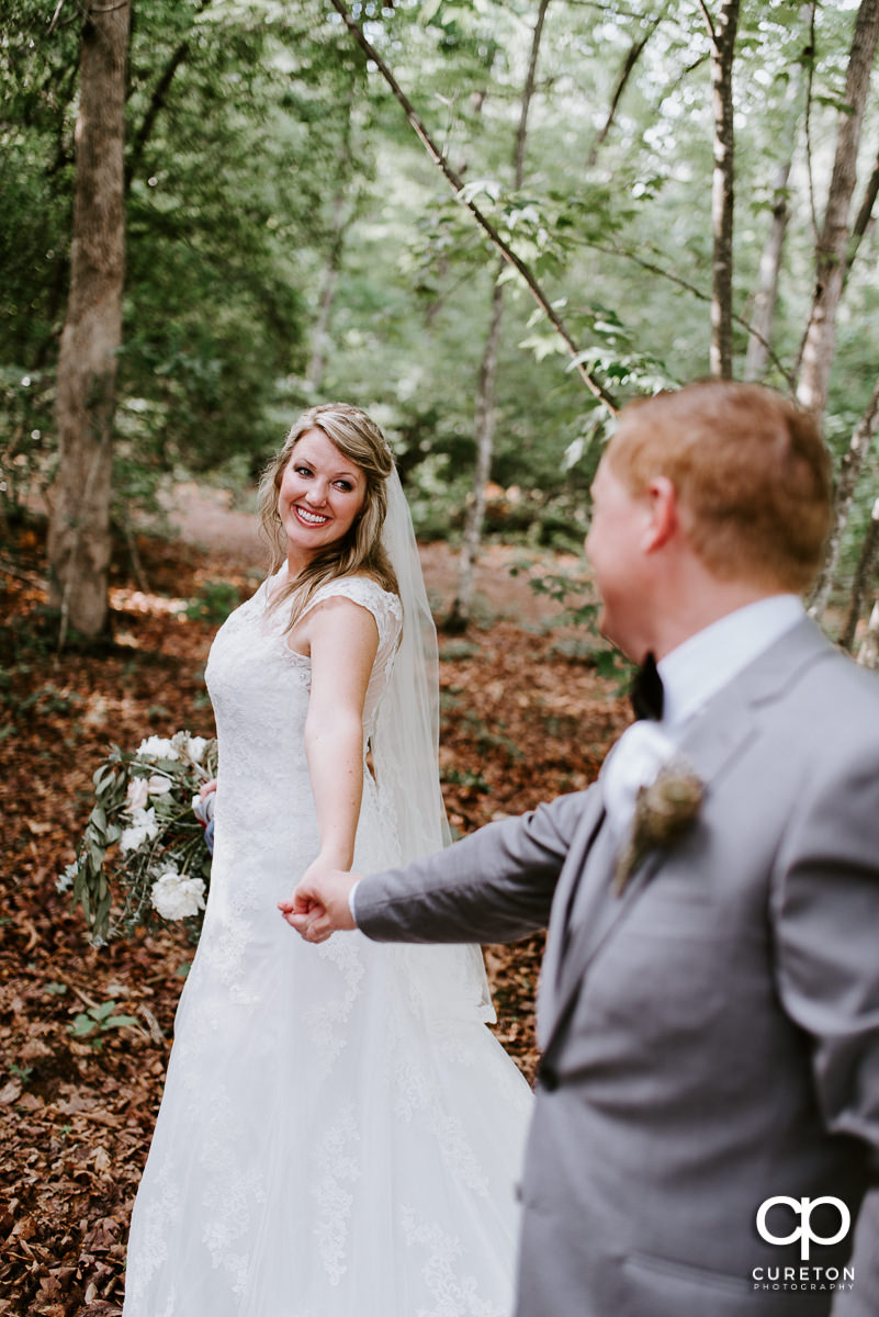 Bride and groom running through the woods at their Hollow at Paris Mountain wedding.
