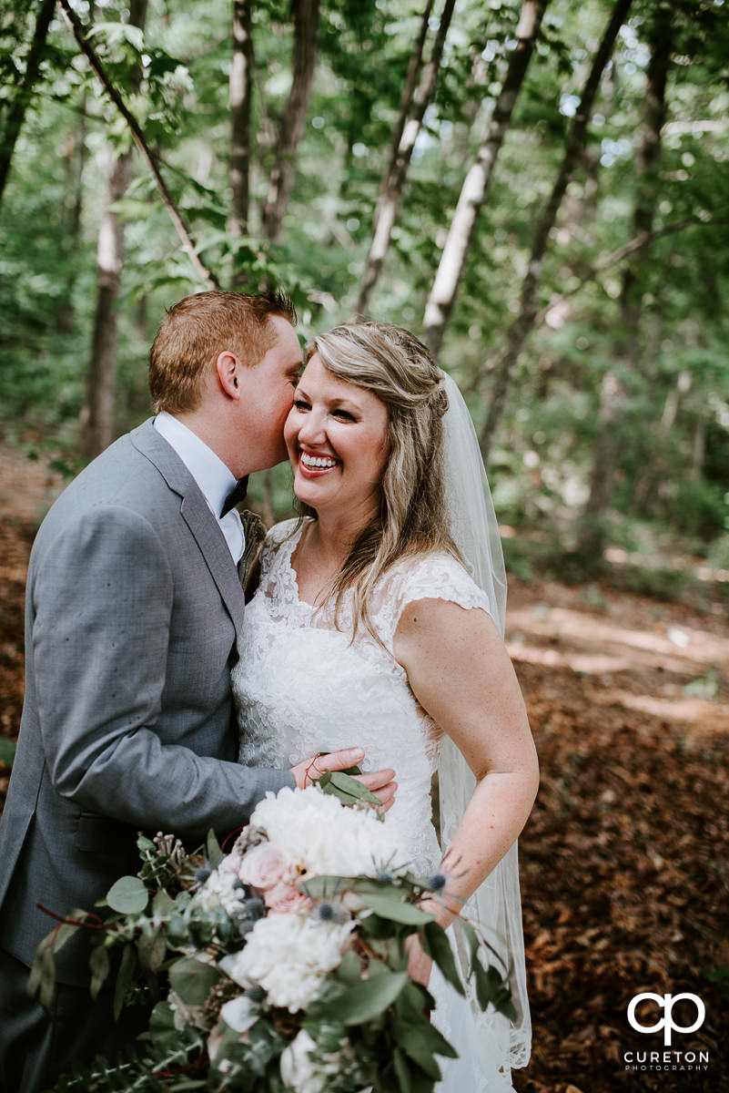 Bride laughing at her groom in rhe woods.