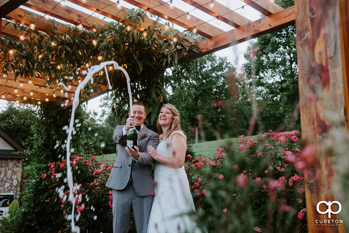 Bride and Groom popping teh cork on some champagne after their Greenville SC wedding.