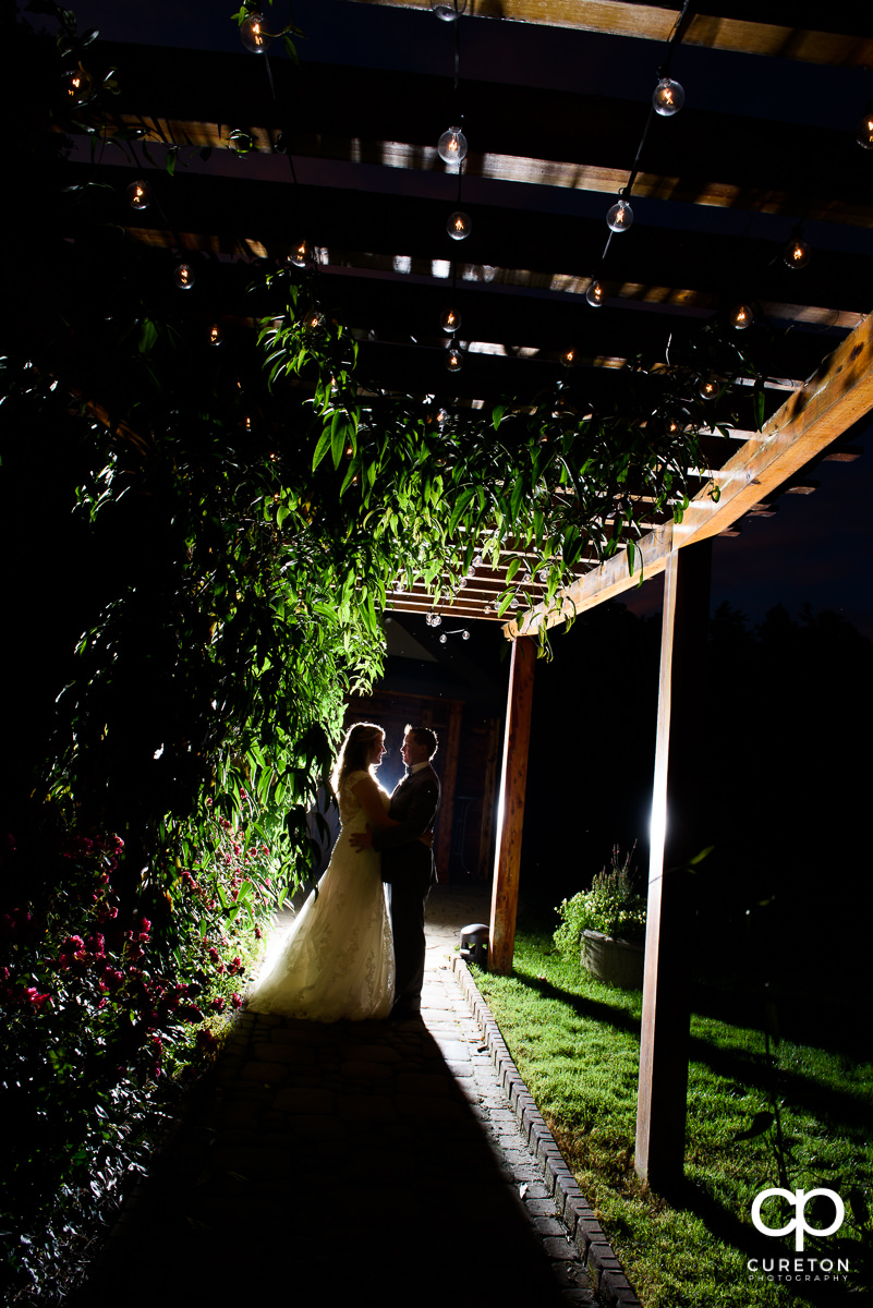 Groom and bride at sunset underneath a portico at The Hollow at Paris Mountain after their wedding.