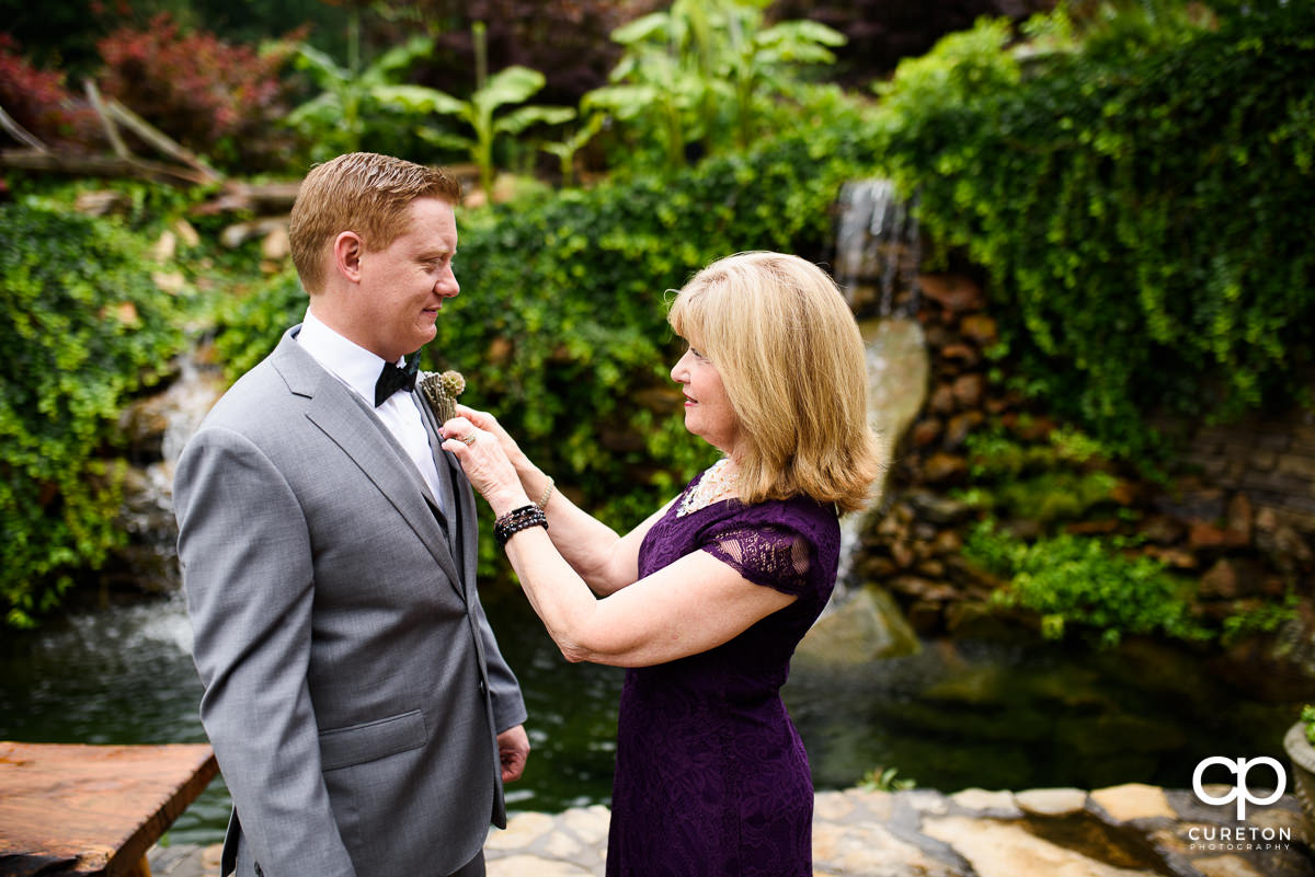 Groom's mother pining a boutonnière on her son.