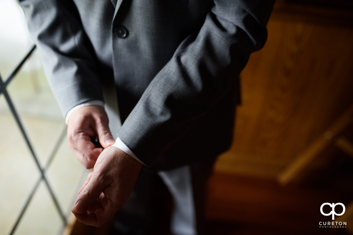 Groom fixing his cuffs.