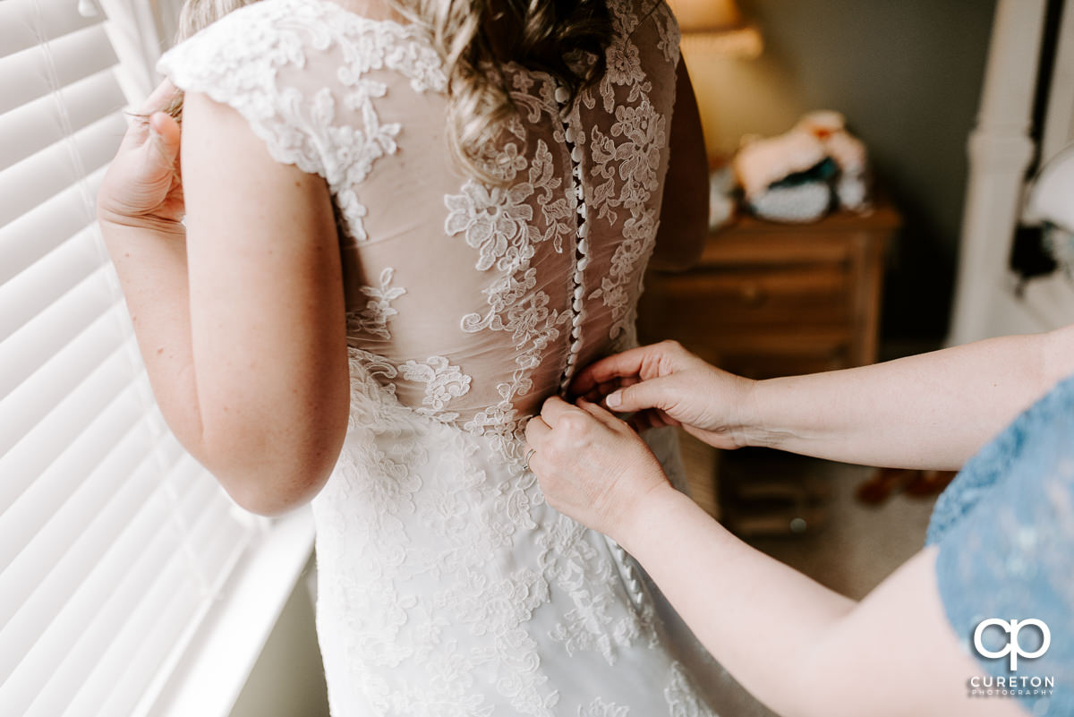 Mother of the bride helping her with her dress before the ceremony.