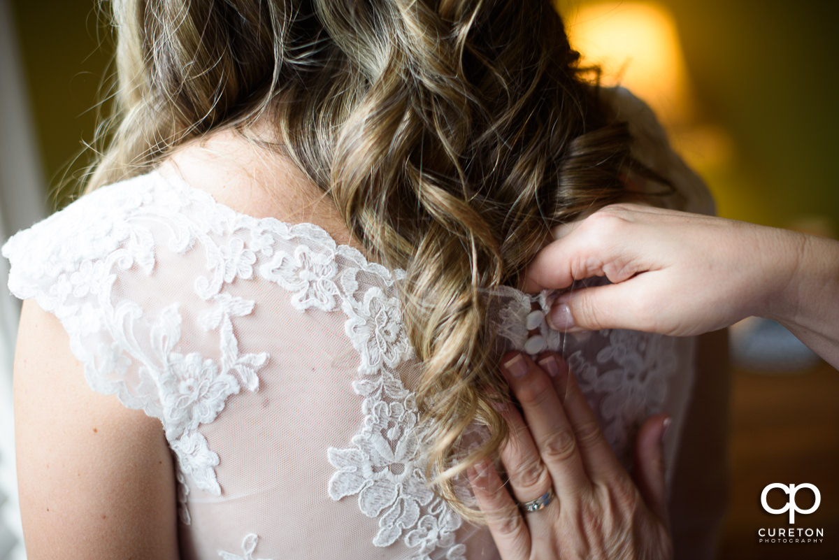 Bride's mom buttoning the back of her dress.