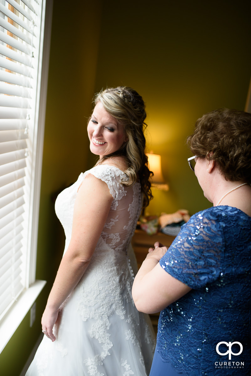 Bride looking back at her mother helping her with her dress.