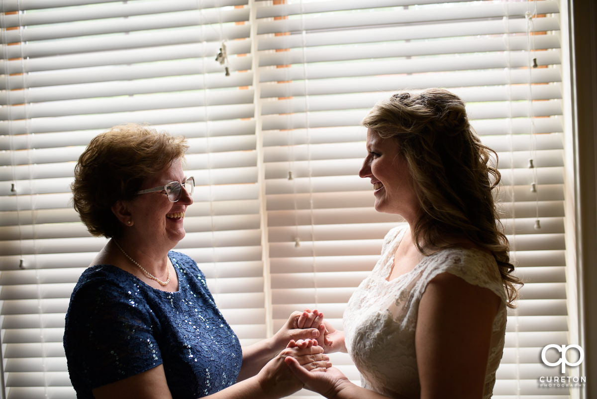 Bride and her mother having a moment in the window before the wedding ceremony at The Hollow at Paris Mountain