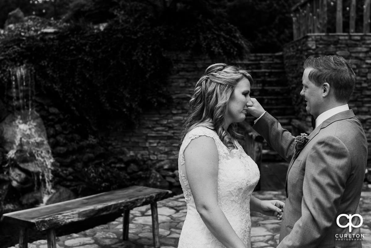 Groom wiping a tear from the bride's face at the first look.