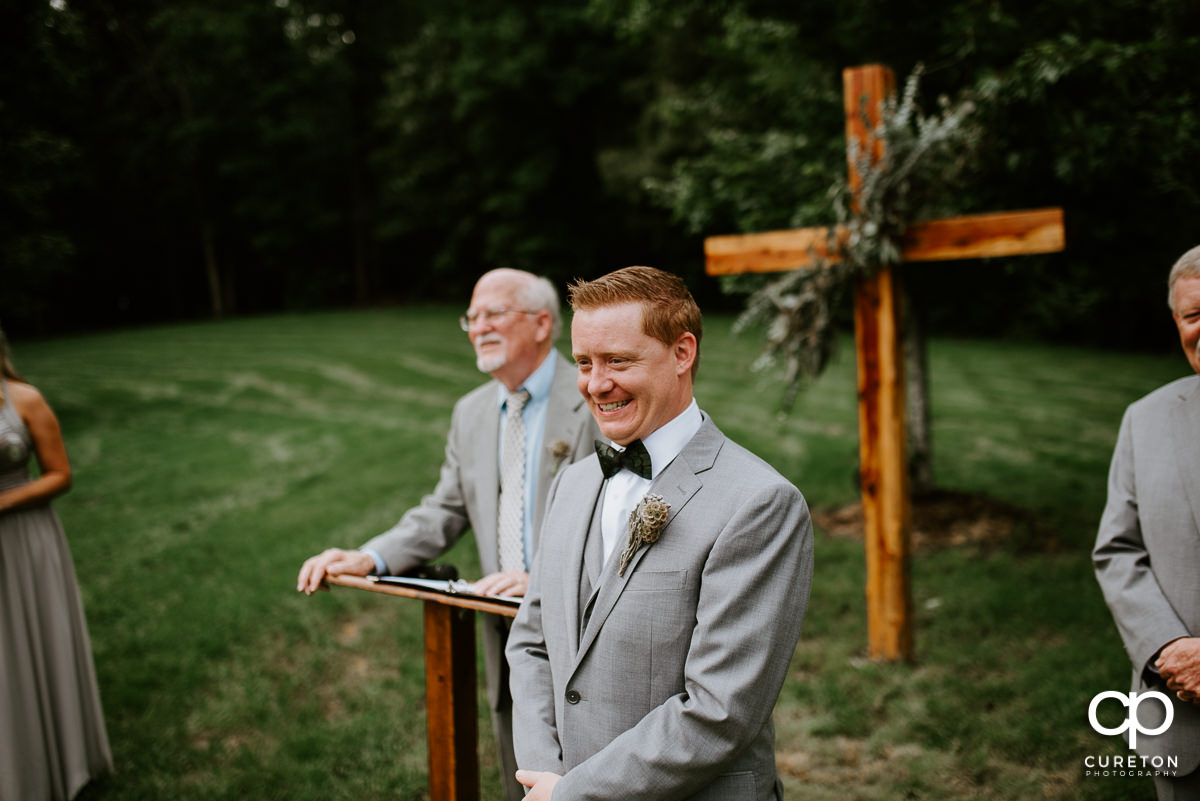 Groom smiling as he sees his bride walking down the aisle for the first time.