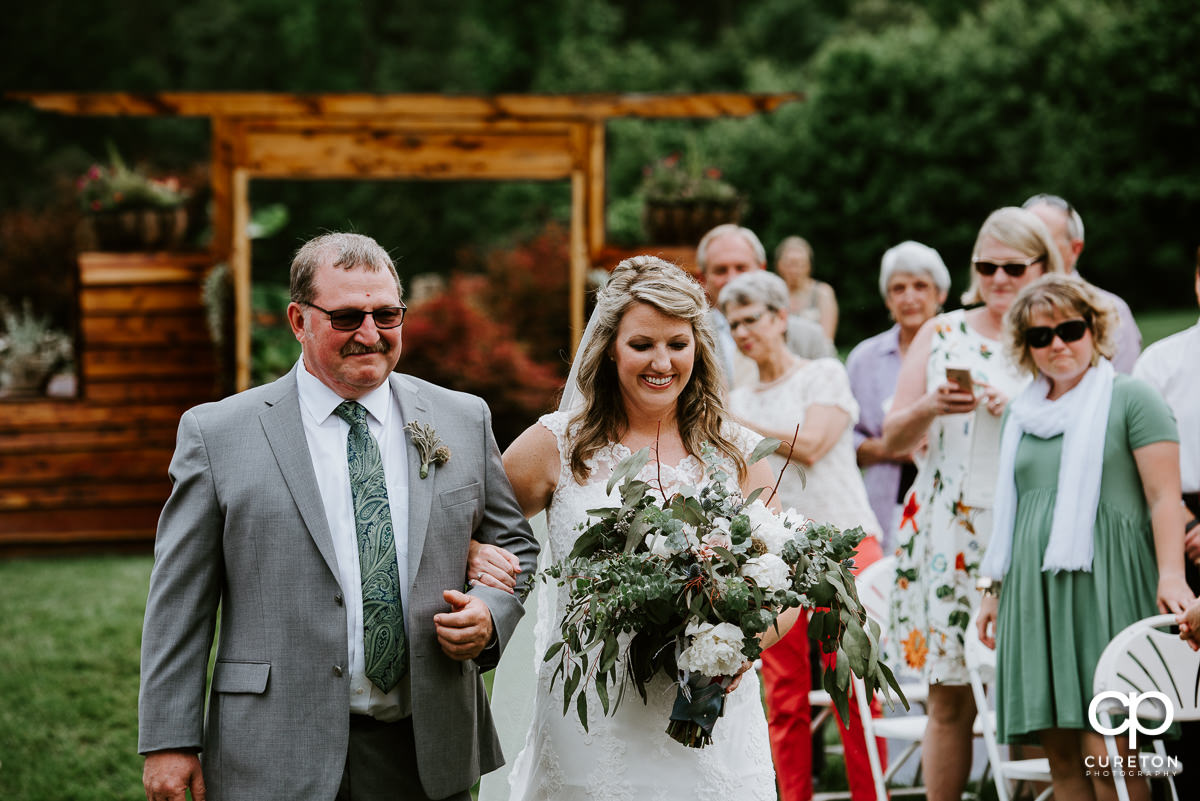 Bride walking down the aisle with her father at The Hollow at Paris Mountain.