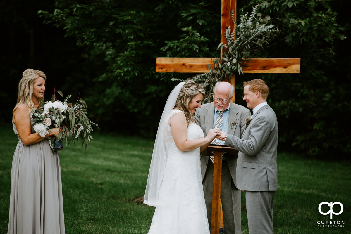 Bride placing a ring on the groom's finger.