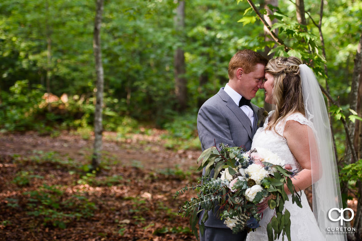 Bride and groom standing nose to nose.