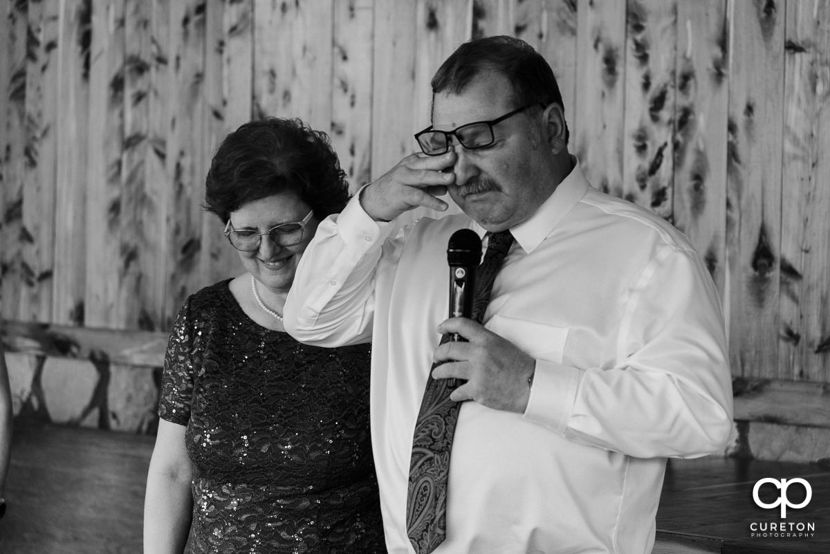 Bride's father tearing up as he gives a speech at the wedding reception.