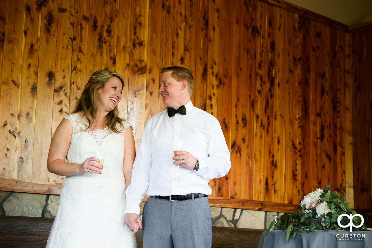 Groom and bride laughing at a speech.
