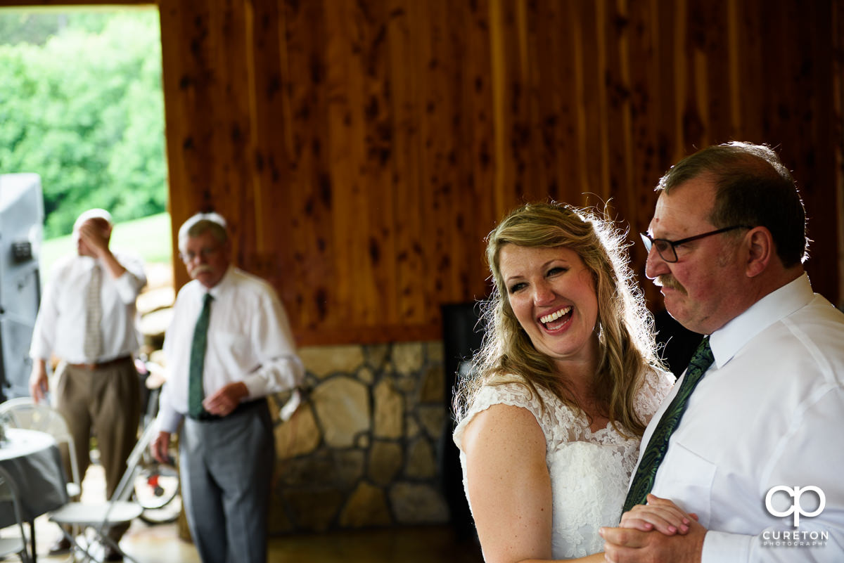 Bride smiling while dancing with her father.