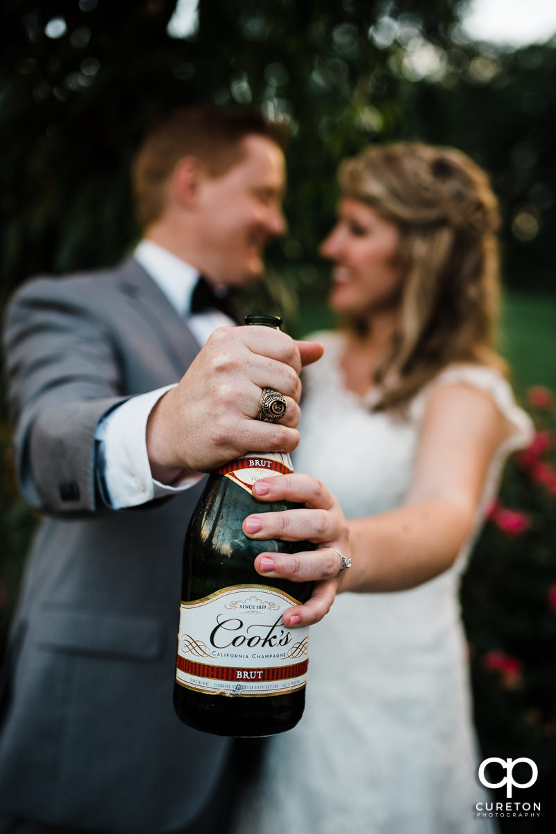 Brode and groom holding a bottle of champagne.