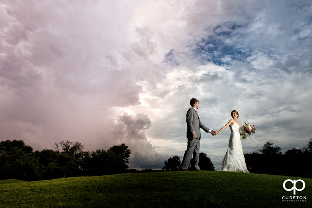 Bride and groom with an amazing sky after their Holly Tree Country Club wedding.