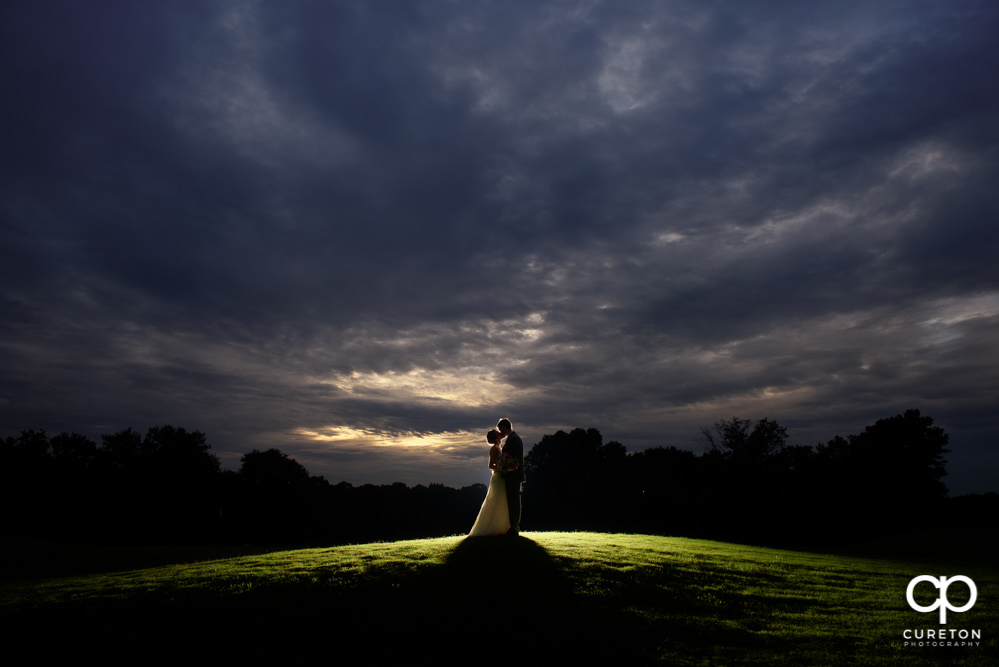 Bride and groom backlit silhouette at sunset after their golf course wedding.