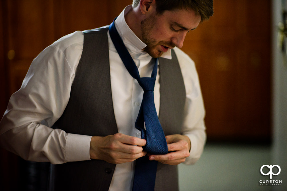 Groom tying his tie .