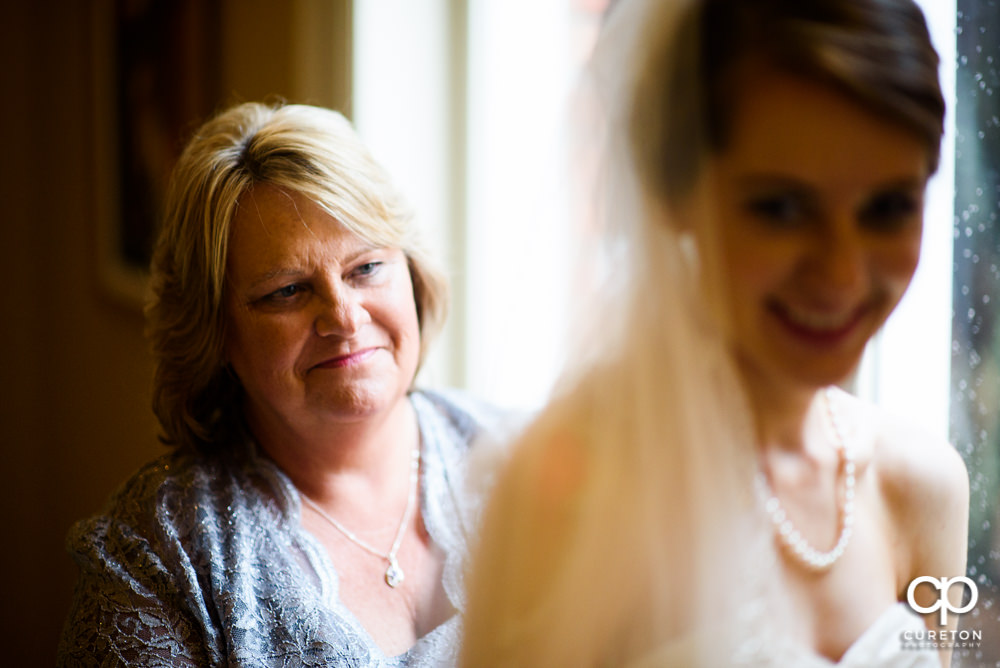 Bride's mom helping the bride int the dress.