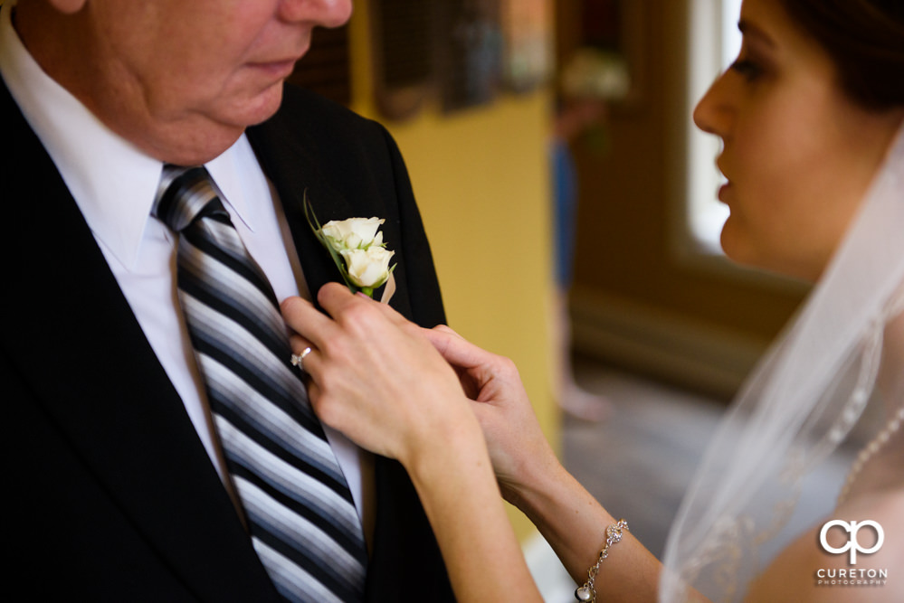 Bride puts dad's boutonnière on.