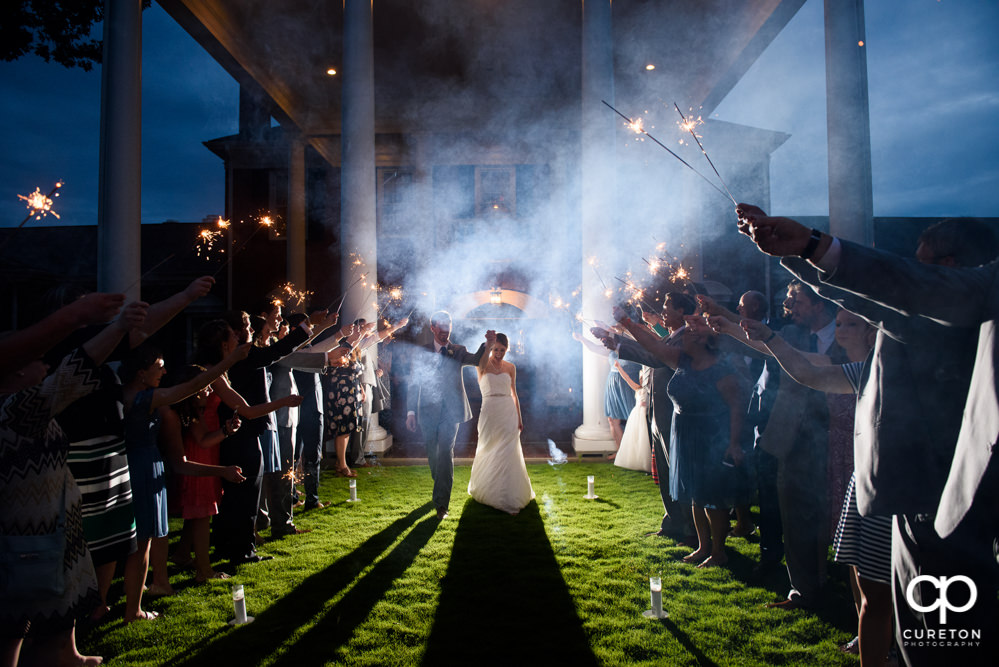 Bride and groom making a grand exit though sparklers after their Holly Tree wedding reception.
