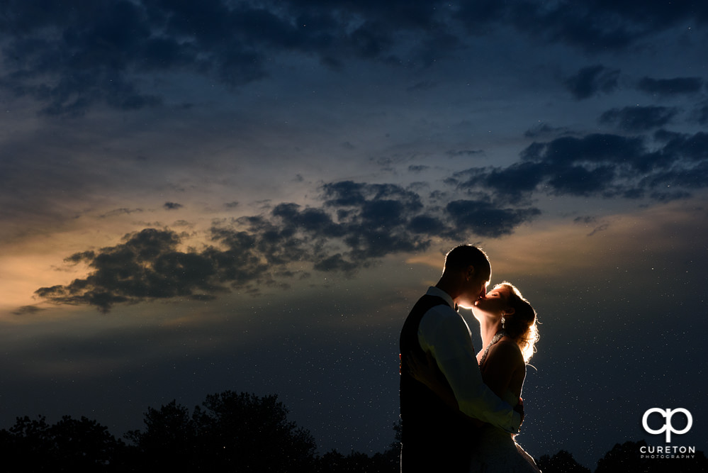 Bride and groom kissing in the sunset.