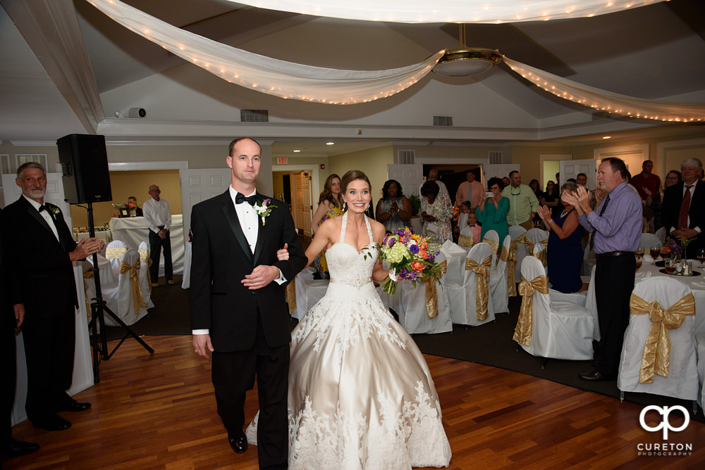 Bride and groom entering the wedding reception at Holly Tree Country Club.