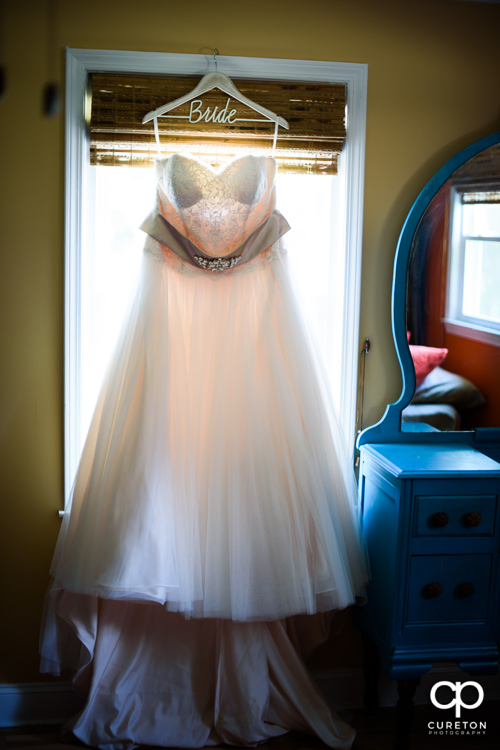 The brides dress hanging in a window.