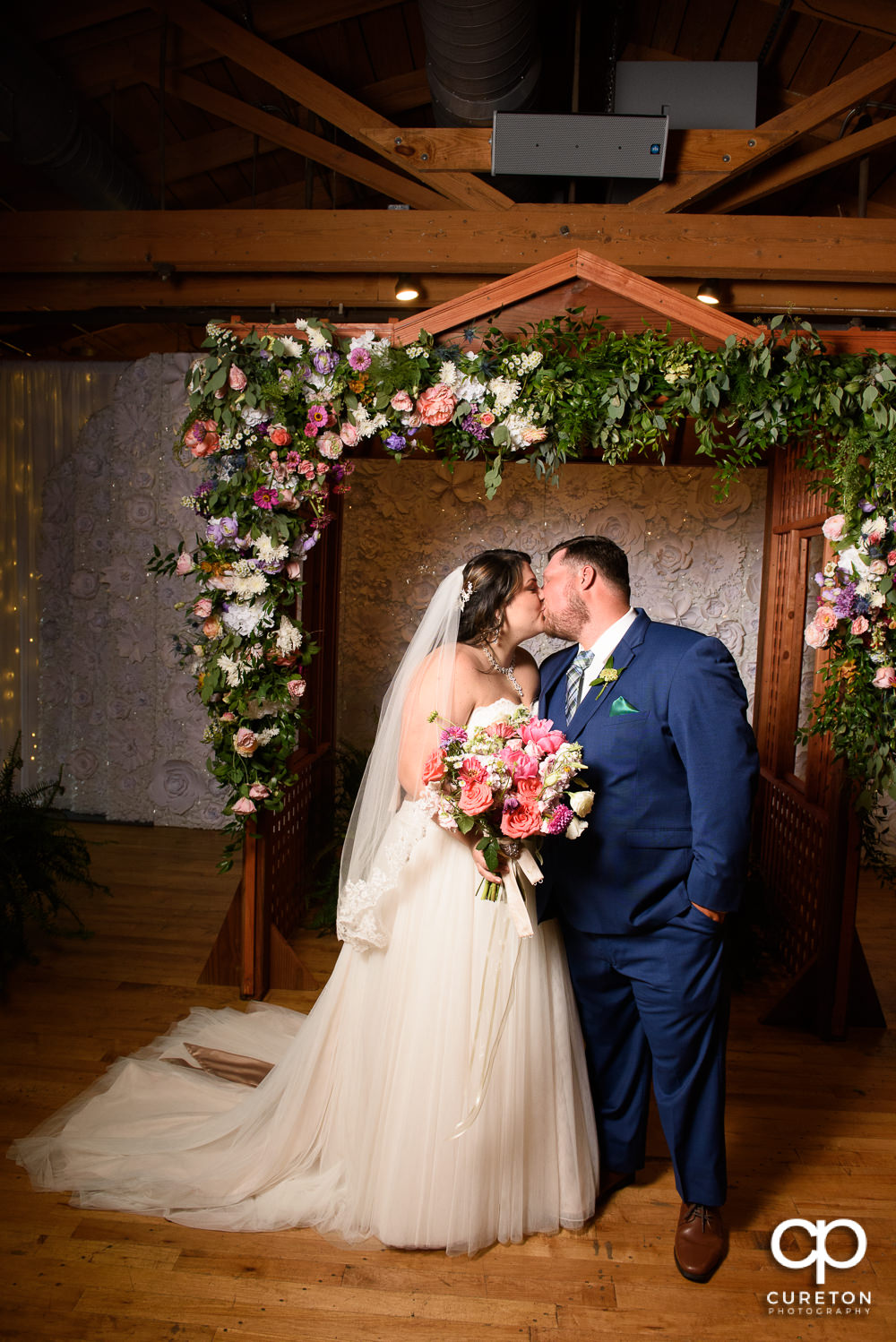 Bride and groom kissing under the arbor at their Huguenot Loft wedding.