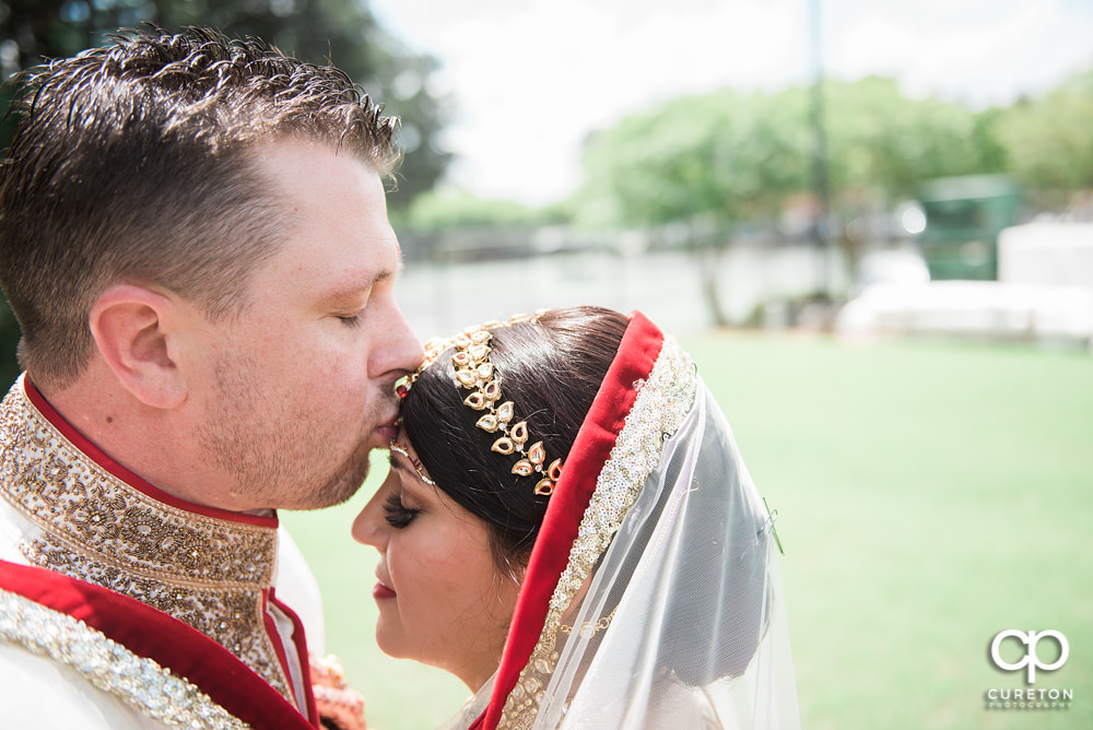 Groom kissing bride on the forehead.