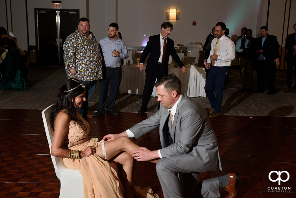 Groom taking off the garter.