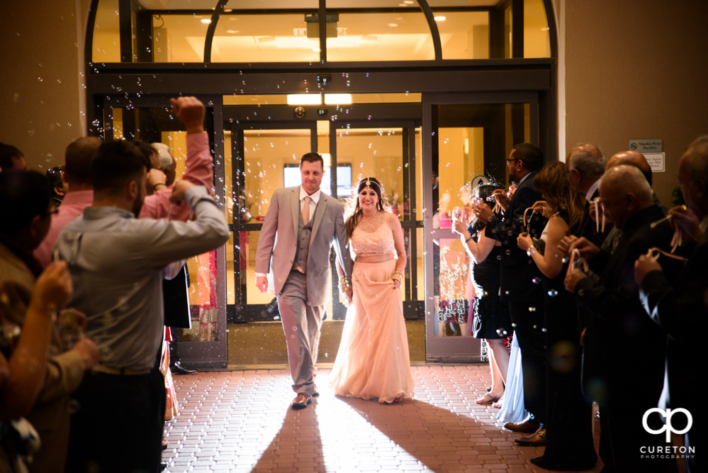 Bride and groom grand exit though bubbles at Embassy Suites.