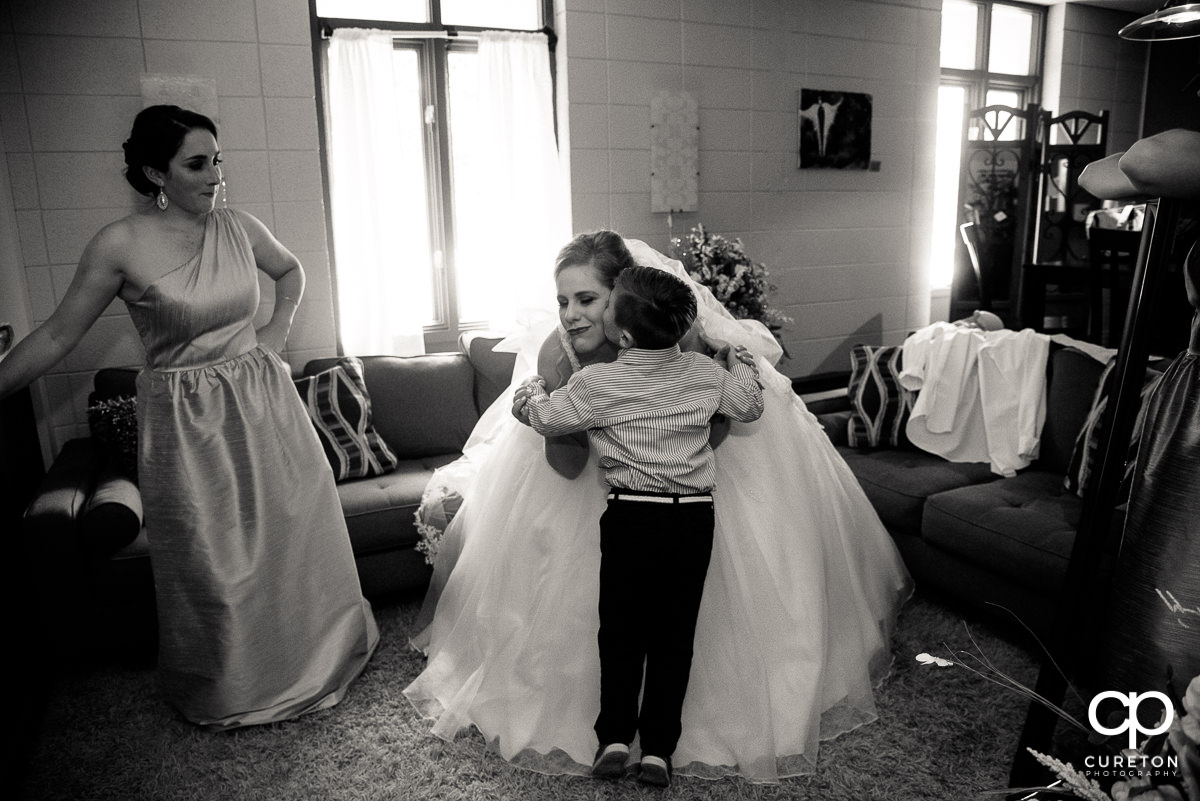 Bride getting kissed on the cheek by a little boy.