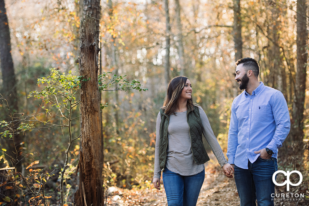 Future bride and groom walking down a trail during their Lake Conestee Nature Park engagement session.