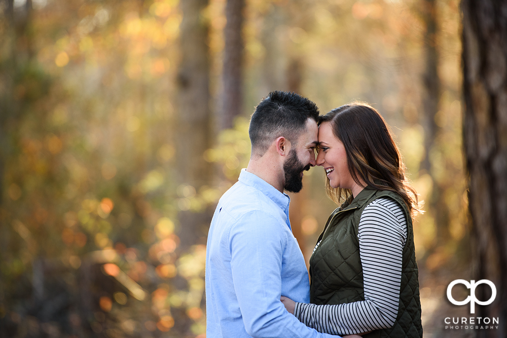 Engaged couple cuddling at Lake Conestee park.