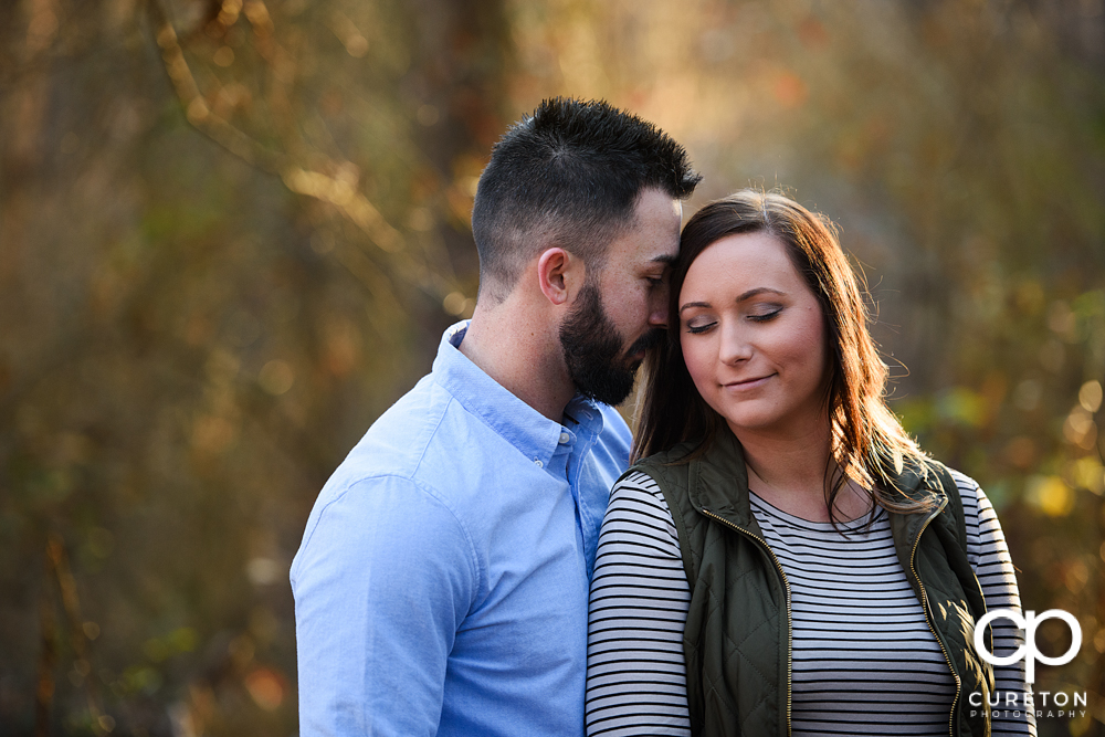 Engaged couple standing in glowing sunlight on the trail.