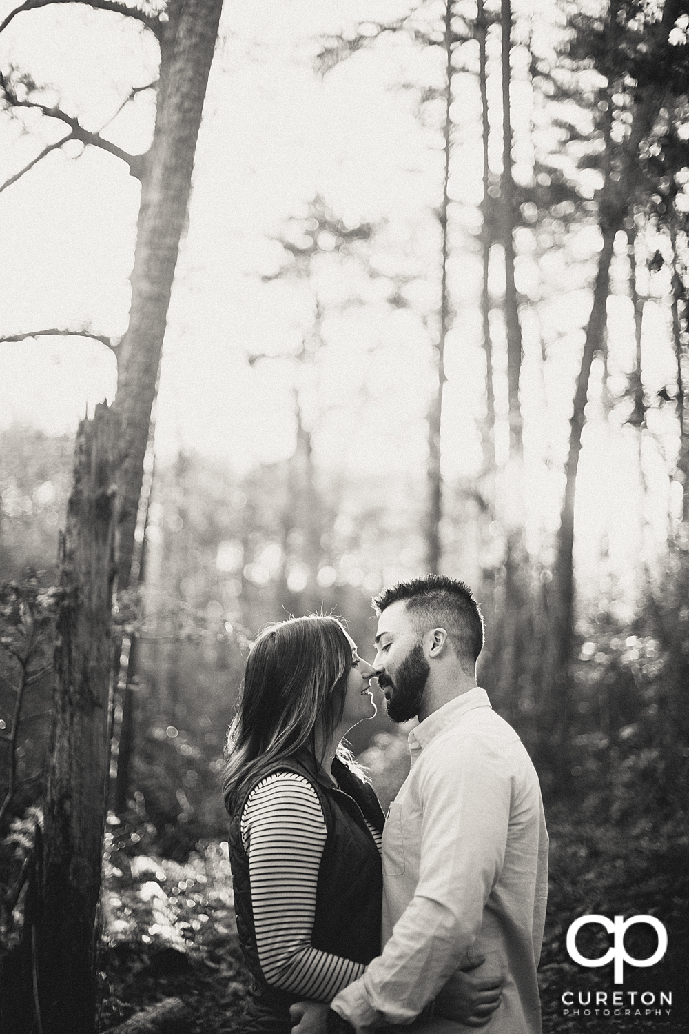Black and white of an engaged couple in the woods.