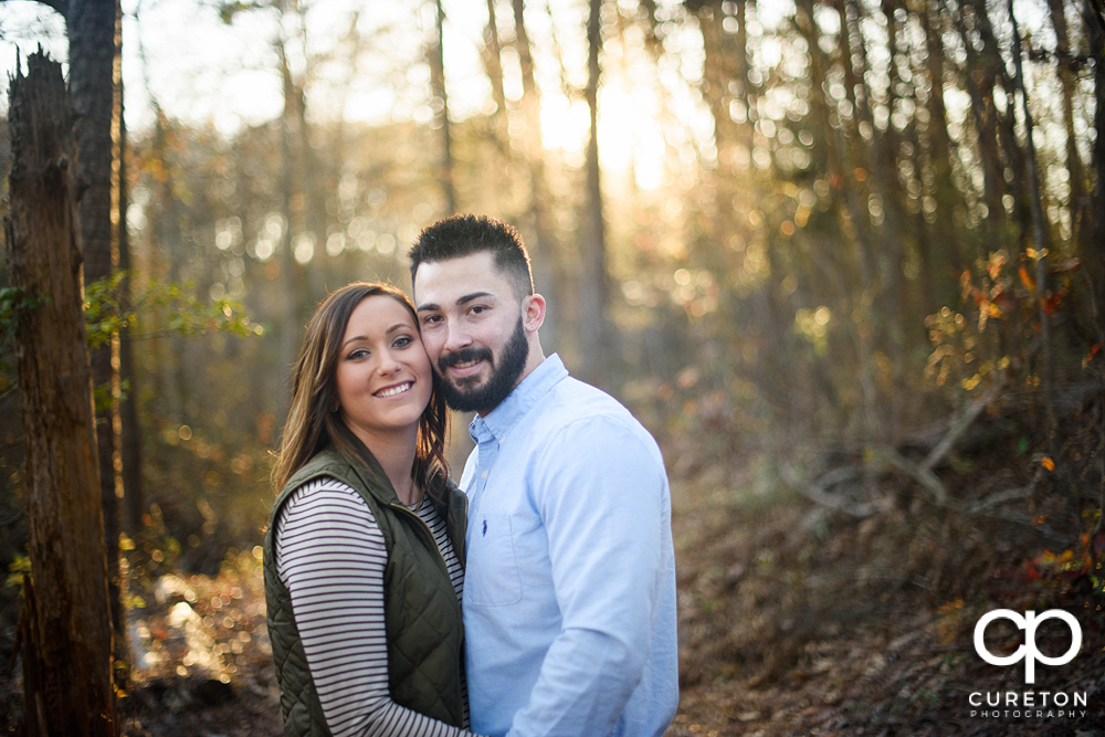 Engaged couple on a trail backlit by the sun.