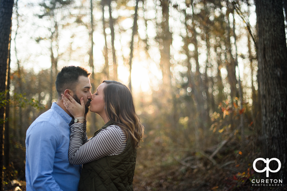 Future bride and groom kissing in the forest during their engagement session in Greenville,SC.