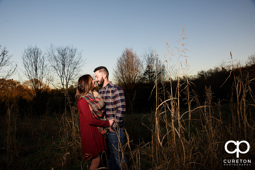 Engaged couple standing in a field.