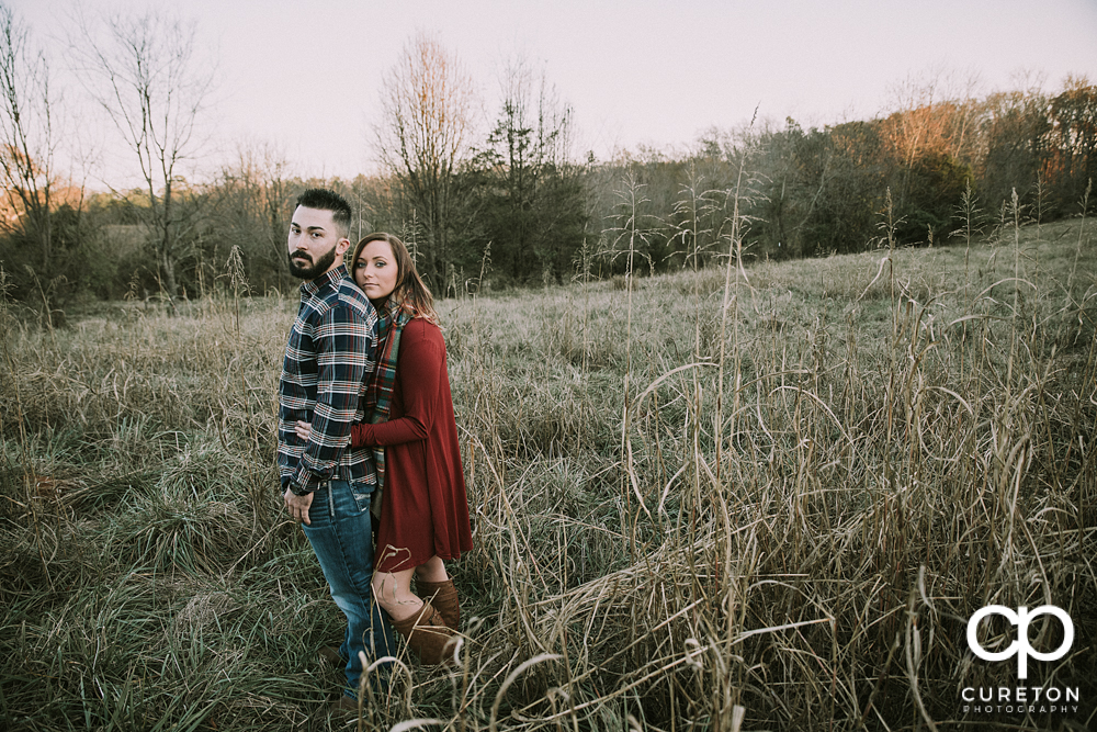 Bride and groom in a field during their Lake Conestee Nature Park engagement session..