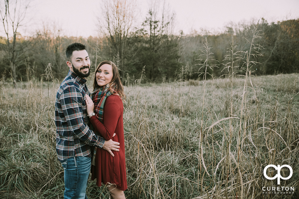 Bride and groom smiling in a field.