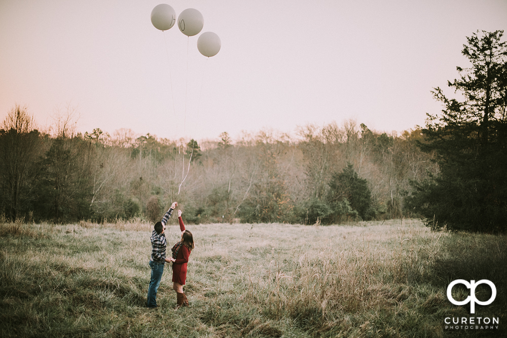 Engaged couple letting of of balloons.