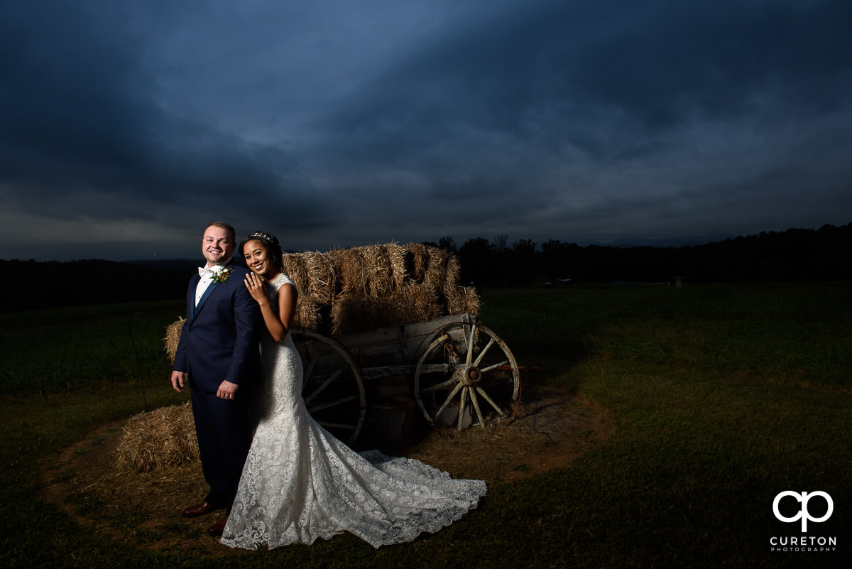 Bride and groom posing by the wagon in the field at Lindsey Plantation.