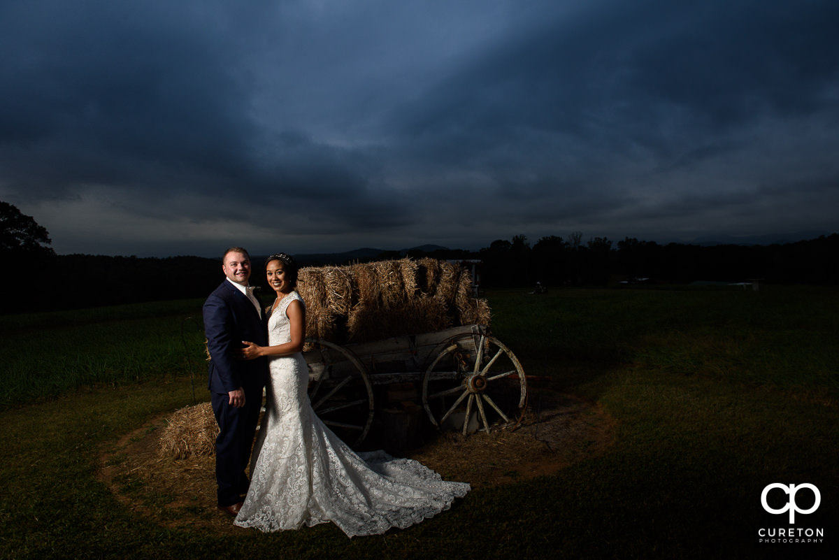 Groom and bride by a wagon at Lindsey Plantation at sunset after their fall wedding.