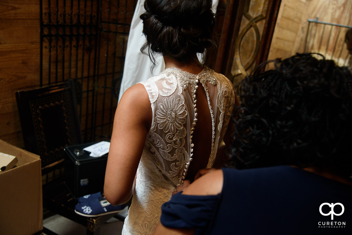 Bride's mom buttoning the back of her dress.